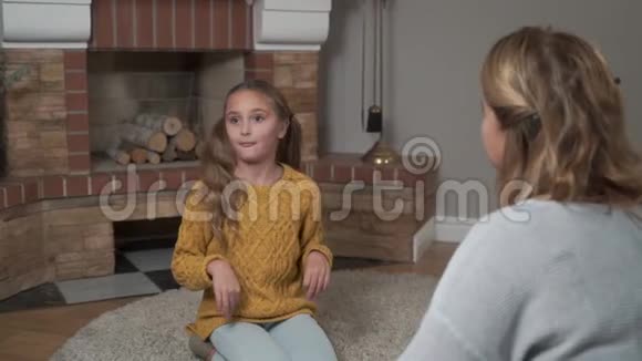 积极的母女俩坐在柔软的地毯上聊天漂亮的高加索女孩在感情上和视频的预览图