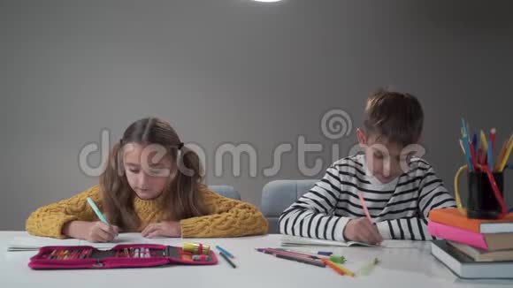 两个白人学童缓慢地翻动笔记本微笑放学后男孩和女孩都很高兴视频的预览图