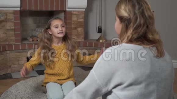 漂亮的白种人小女孩在家里坐在柔软的地毯上有感情地说话和打手势她母亲视频的预览图