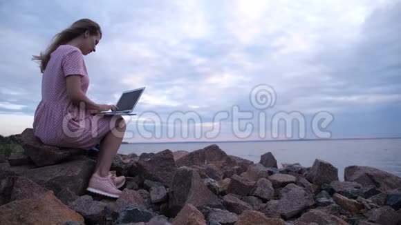 在户外工作在海边码头上的女人用笔记本电脑打字4K慢慢视频的预览图