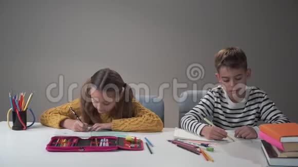 两个白人孩子坐在家里的桌子上做作业精疲力竭的男孩把头撞向视频的预览图