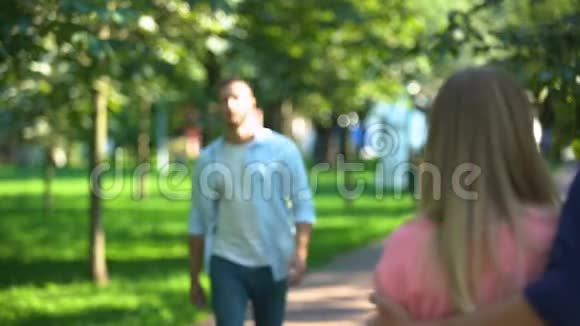 在公园散步时男人和女朋友争吵看着另一个男人视频的预览图