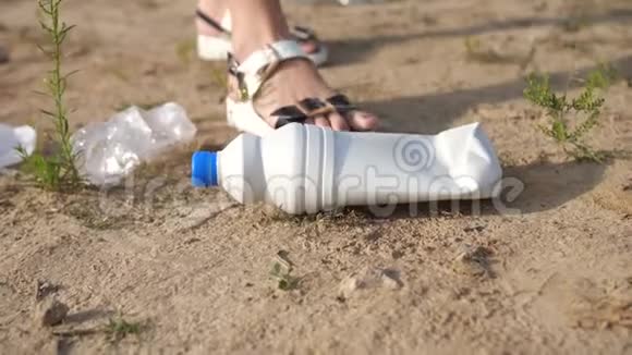 特写镜头一个女人从地上举起一个塑料瓶把它放进一个袋子里志愿者用塑料清洁海岸视频的预览图