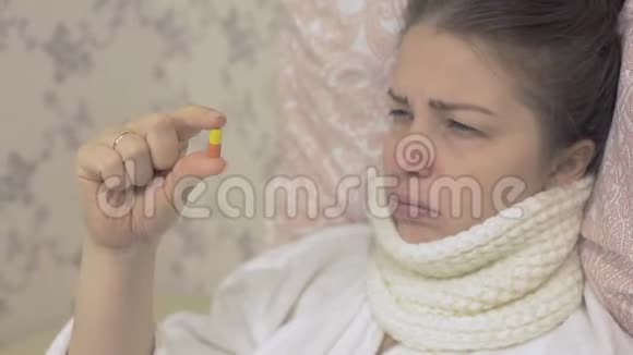 一个年轻的女人拿着一颗红白相间的药丸照顾你的健康视频的预览图