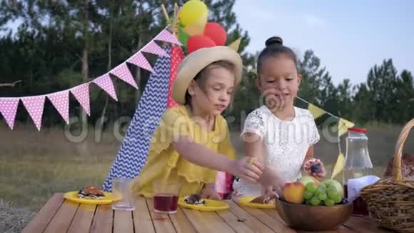 小饥饿的女孩在户外周末的背景下在森林野餐的下午吃水果视频的预览图