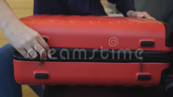 特写的女人把机场大厅的红色大行李箱盖好把他放在地板上视频的预览图