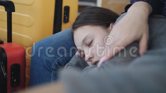 在机场候机室的椅子上睡在妈妈旁边的少女特写镜头航班延误视频的预览图