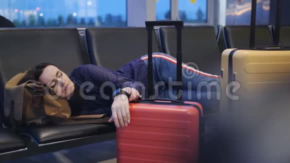 机场的女商人醒来时看着手表航班之间的时间在长椅上睡觉的女人视频的预览图