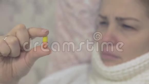 一个年轻的女人拿着一颗红白相间的药丸照顾你的健康视频的预览图