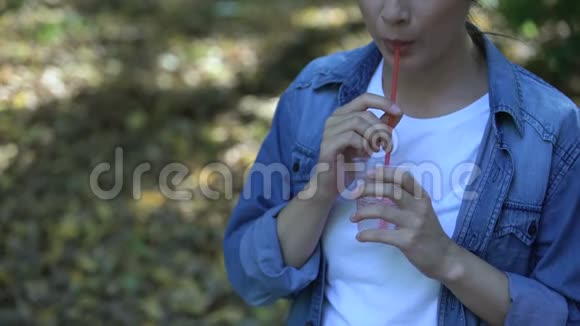 粗心的年轻女人在公园里喝苏打水扔塑料吸管垃圾视频的预览图