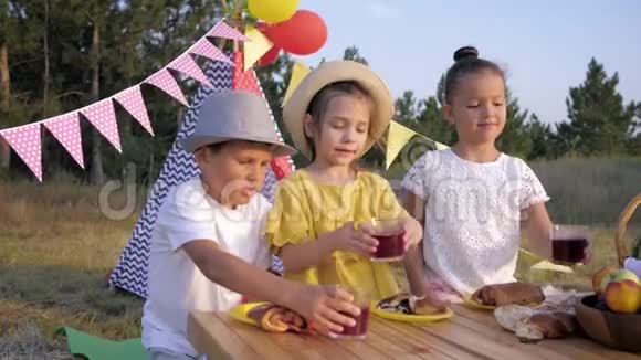 有趣的孩子们快乐的孩子们从桌子上拿着果汁的玻璃杯在日落时解渴视频的预览图