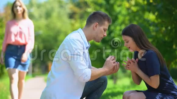 天真的女孩在欣赏结婚戒指而她的男朋友在看着另一个女人视频的预览图