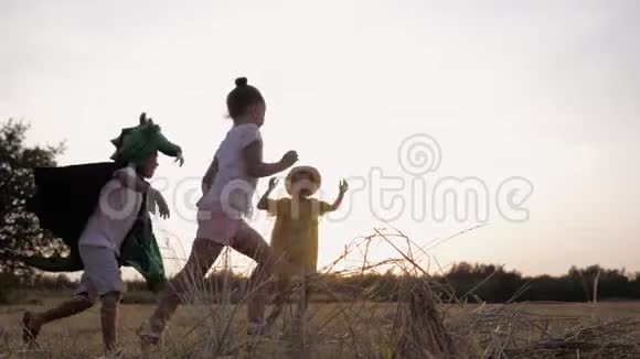 快乐的消遣穿着龙服的男孩子在日落时分和女朋友在草地上跑来跑去玩游戏视频的预览图