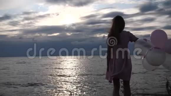 全景在夕阳的天空和大海的背景下有球的女孩4K慢Mo视频的预览图