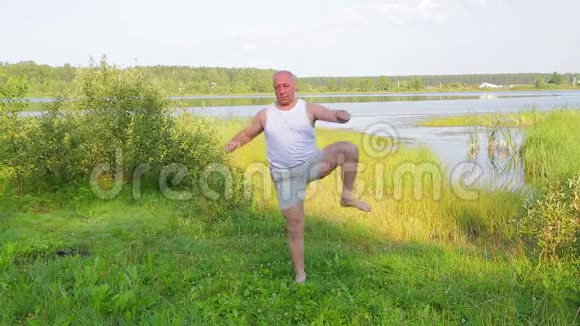 一位老人早上在湖岸上用脚做体育锻炼视频的预览图