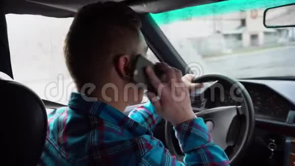 一个年轻人开车打电话雨天从后座看到一个男人的后视图视频的预览图