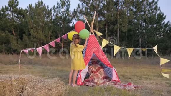 小朋友用气球和野餐毯装饰草地在森林里的周末户外野餐视频的预览图