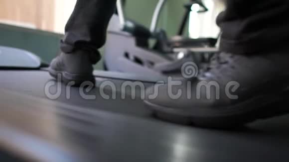 年轻的男性脚在健身俱乐部里慢动作的跑步机上行走视频的预览图