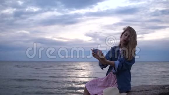 海上的年轻女子在夕阳的背景下在手机上自拍4K慢慢视频的预览图