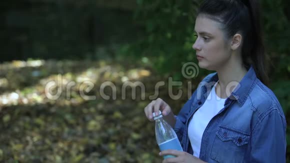 粗心的女性消费者在森林里扔水瓶塑料垃圾视频的预览图