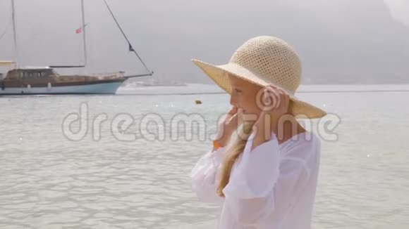 肖像少女戴草帽观看海上和船舶背景一个双手捧着帽子的漂亮女孩在大海中尽情享受视频的预览图