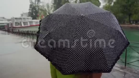 女人带着可爱的黑色圆点伞走在长廊上后景伞的特写视频的预览图