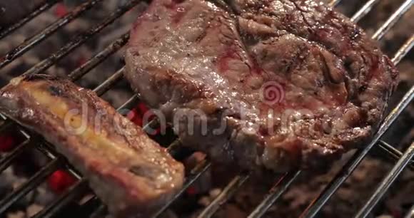 大块多汁的牛肉肉煎在烤架上血液散发翻倒在另一方烟和蒸汽木柴视频的预览图