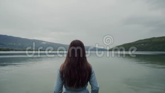 长长的黑发女人站着欣赏风景优美的阿尔卑斯山和的后景视频的预览图