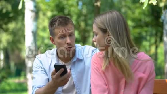 愤怒的男人对妻子大喊大叫看着她手机上的信息嫉妒视频的预览图
