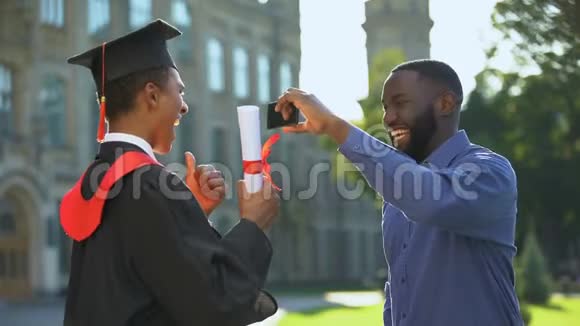 黑人男子为十几岁的儿子拍毕业礼服竖起大拇指视频的预览图