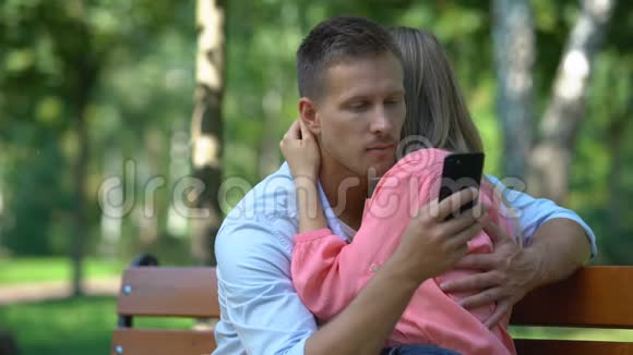 一对情侣在公园拥抱男友给另一个女孩发短信背叛视频的预览图