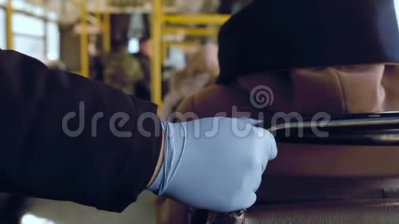 在COVID19冠状病毒流行期间公共交通工具中戴着橡胶手套的人手扶扶手栏杆视频的预览图