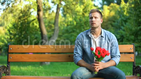 男人带着一束花厌倦了等待女朋友走开了糟糕的约会视频的预览图