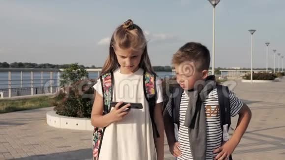 学校的朋友男孩和女孩走路和看智能手机视频的预览图
