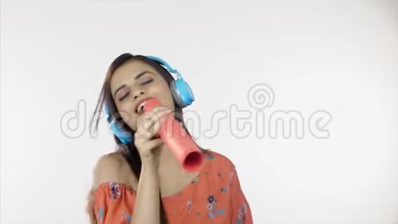 年轻女孩听她最喜欢的歌曲使用蓝色耳机休闲概念视频的预览图