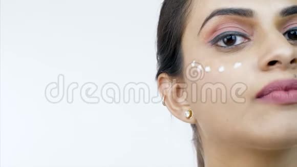 一名印第安妇女在白色背景下将粉底涂在脸上视频的预览图