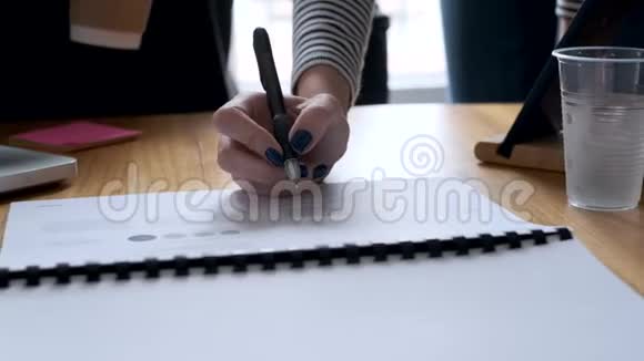一个女人的手在报纸上指指点点地写着办公室里的一个新项目视频的预览图