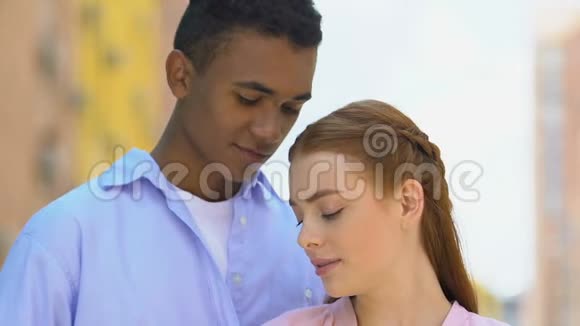 年轻的黑人男性温柔地拥抱红发女友一对享受约会的情侣视频的预览图