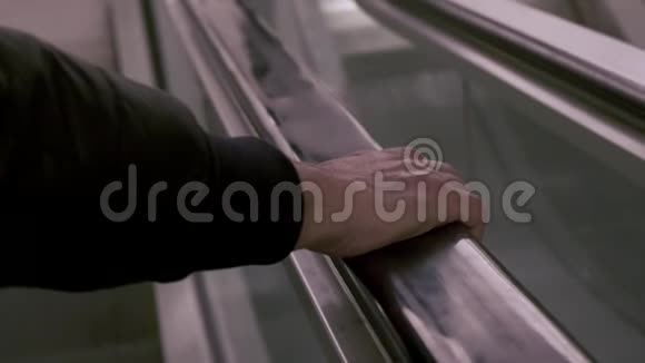 扶梯下移时扶手黑色橡胶扶手上男性手的特写视频的预览图