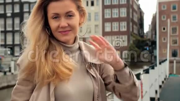 一个美丽的金发女人微笑的肖像在历史中心的房子和运河的背景下视频的预览图