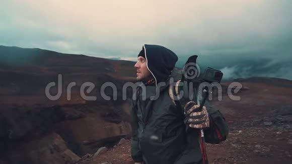 穿着雨衣的人拿着棍子在火山上为北欧人行走看着远方视频的预览图