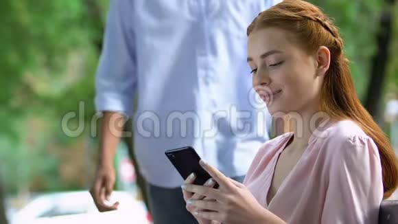 玩手机的朋友嘲笑女孩沉迷于社交网络视频的预览图