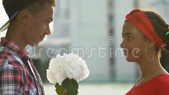微笑着的黑人男孩送心爱的女孩一束鲜花生日礼物视频的预览图