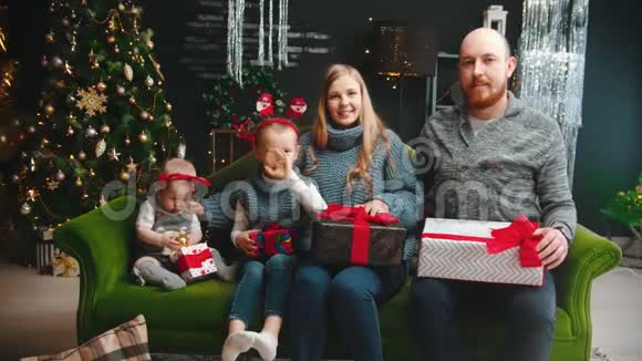 圣诞节概念一家人坐在沙发上挥舞双手视频的预览图