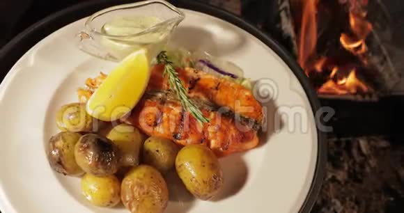 烤鱼放在白色盘子里上面有土豆柠檬和酱汁赤焰红煤烟柴火视频的预览图