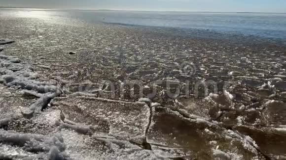 冰片漂浮在波浪上冰斑块沙质海岸石头春天的景观阳光明媚的天气安抚视频的预览图