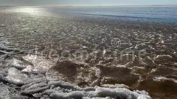冰片漂浮在波浪上冰斑块沙质海岸石头春天的景观阳光明媚的天气安抚视频的预览图