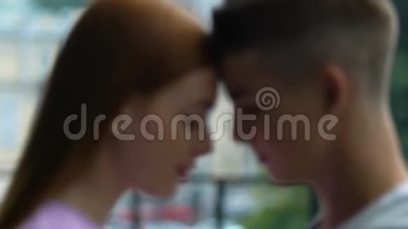 漂亮的红发女孩和十几岁的男人摸着额头带着爱看着视频的预览图