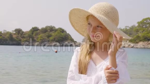 蓝色海洋背景上戴草帽的可爱少年女孩肖像在夏季行动美丽的少女装扮视频的预览图