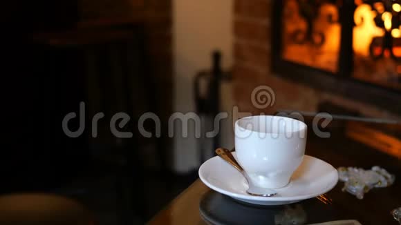 咖啡杯放在有壁炉的咖啡厅或餐厅的桌子上桌上闪着火焰浪漫的环境视频的预览图